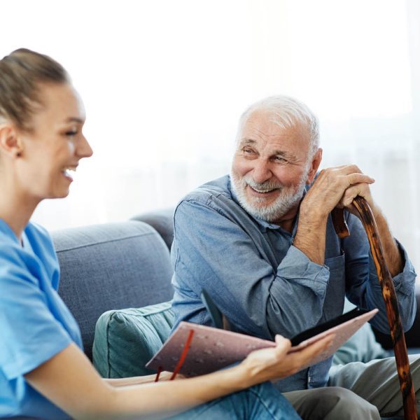 nurse doctor senior care caregiver photo album help assistence r Doctor or nurse caregiver with senior man looking at photo album and picture  at home or nursing home