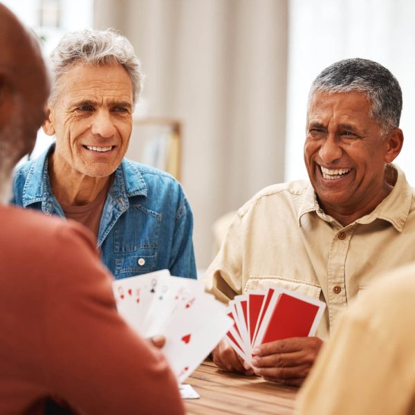 Senior man, friends and laughing for card games on wooden table in fun activity, social bonding or gathering. Group of happy elderly men with cards for poker game enjoying play time together at home Senior man, friends and laughing for card games on wooden table in fun activity, social bonding or gathering. Group of happy elderly men with cards for poker game enjoying play time together at home.